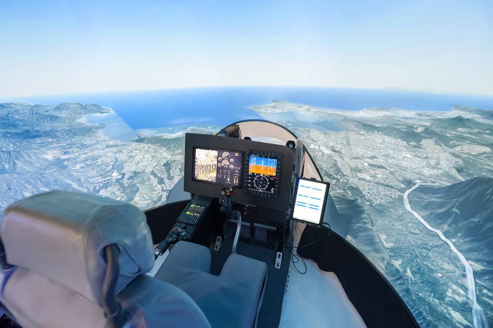Flight simulator cockpit with view of landscape and control panels for pilot training